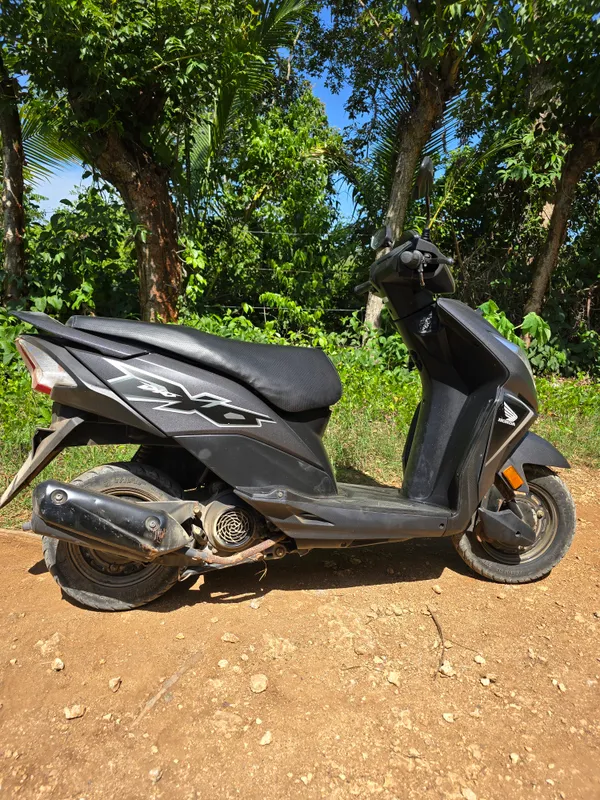 A scooter in side profile on a dirt road on Utila