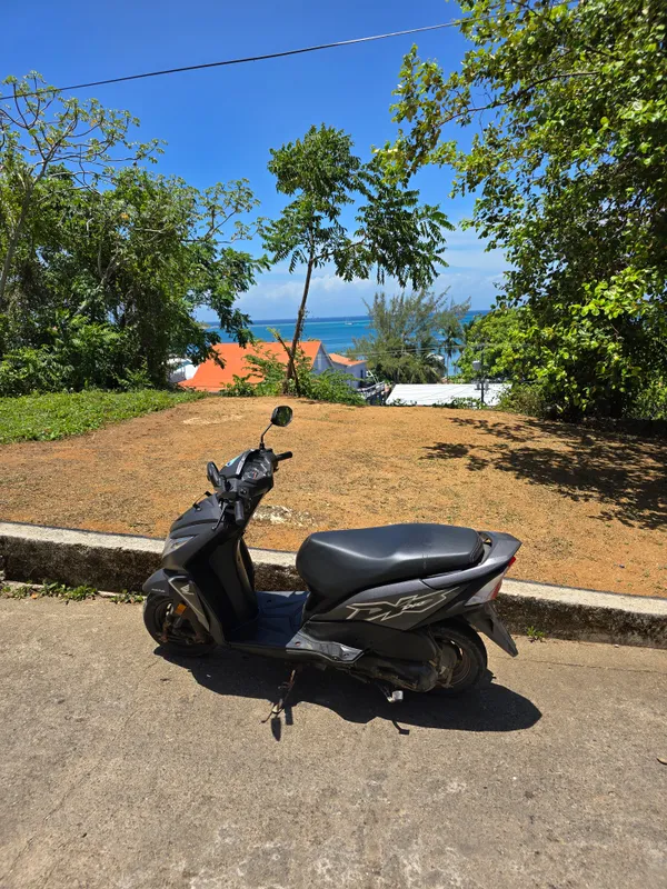 Una moto sobre concreto con borde de tierra en Utila
